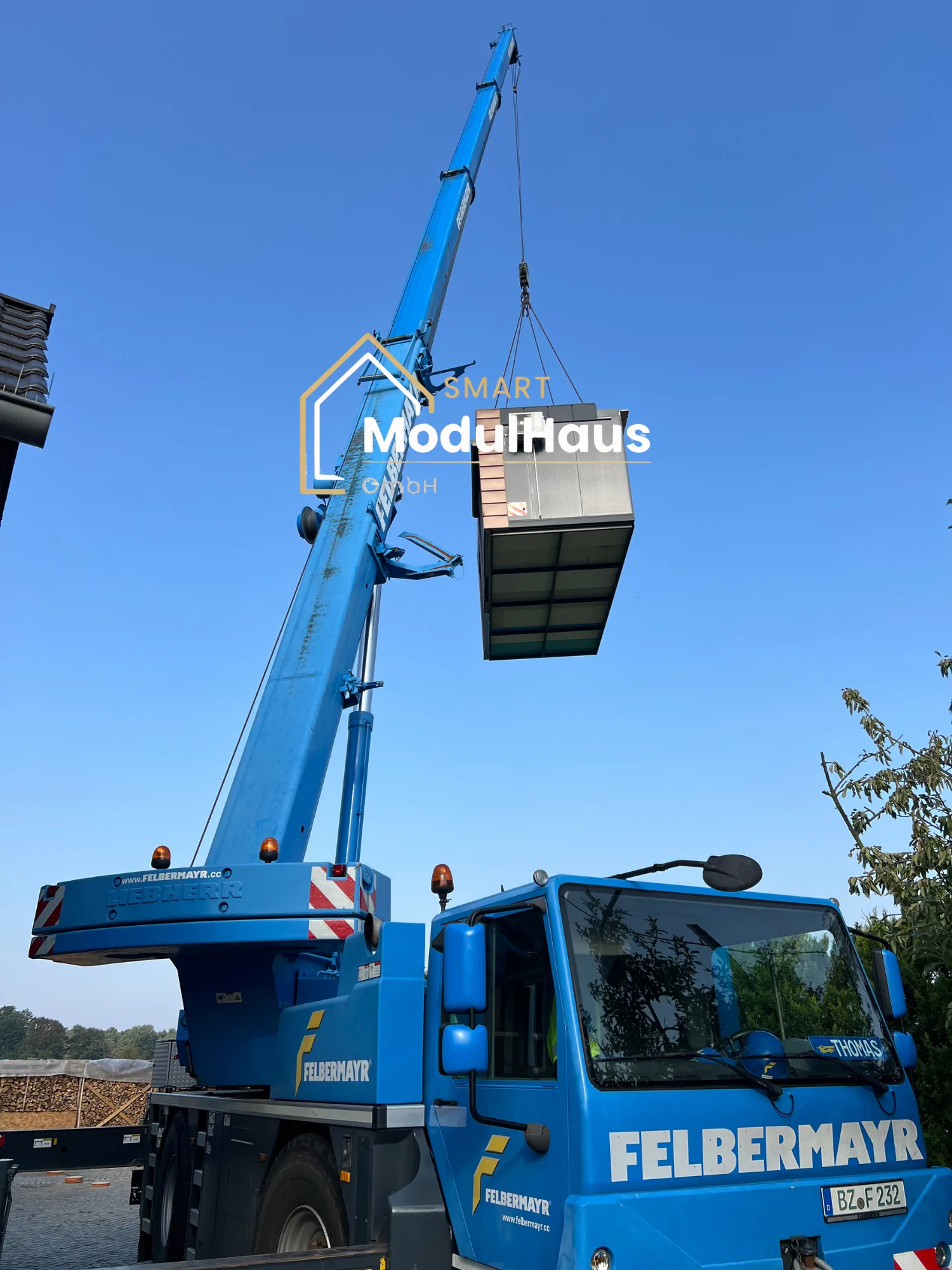 Mobilkran hebt ein Modulhaus über das Grundstück zum Fundament
