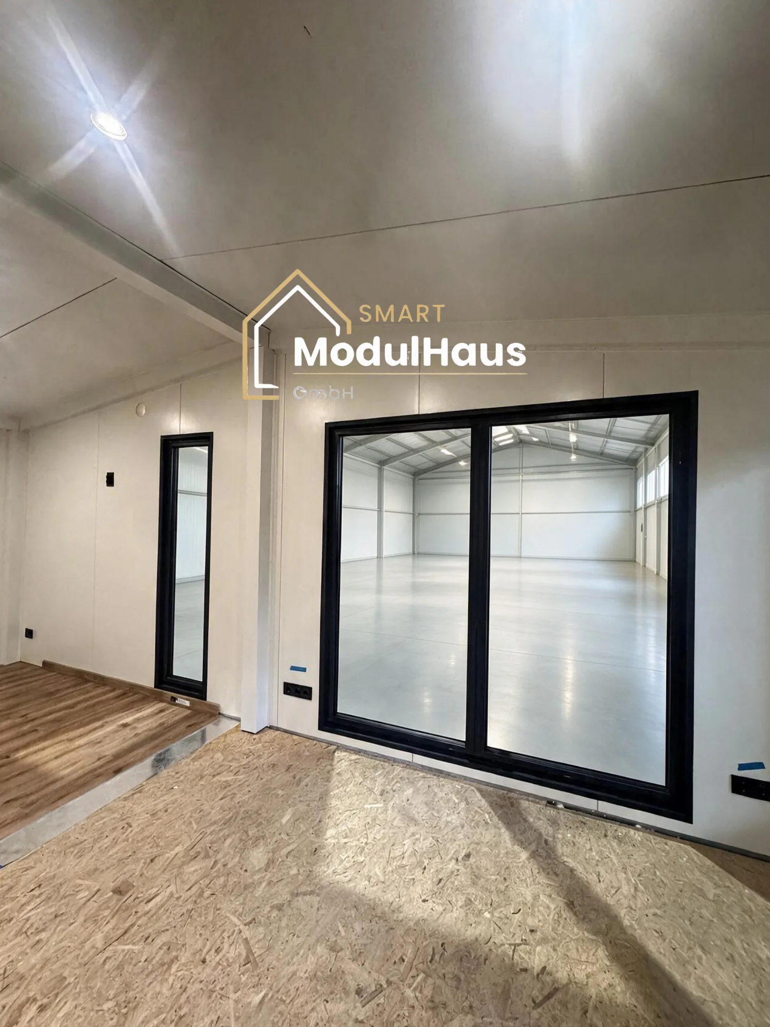 Fertig eingebaute Fenster und Türen eines Moduls, Blick aus dem Modul in die Produktionshalle